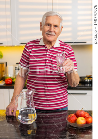 Senior old man drinking fresh water in kitchen at home for hydration diet wellness healthy lifestyle Senior old man drinking fresh water in kitchen at home for hydration diet wellness healthy lifestyle 140747076