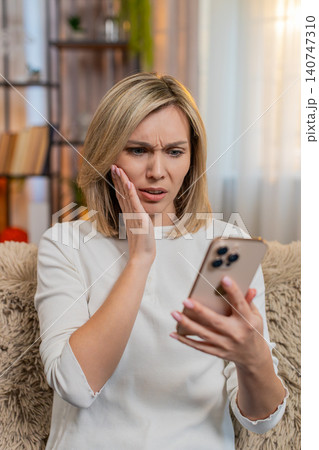 Adult woman disappointed by bad news on smartphone at home sighs with frustration emotional reaction Adult woman disappointed by bad news on smartphone at home sighs with frustration emotional reaction 140747310