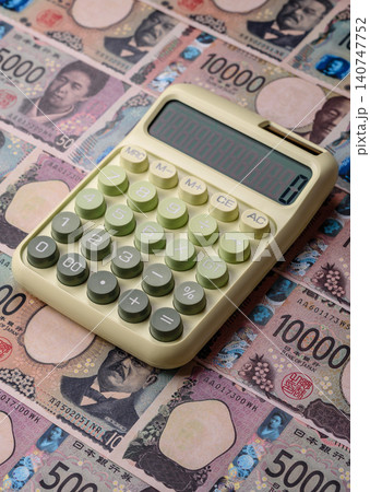 A calculator with Japanese Yen banknotes. A calculator with Japanese currency A calculator with Japanese Yen banknotes. A calculator with Japanese currency 140747752