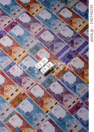 A silver bar, white metal against a backdrop of Qatari money, as a concept. A silver bar A silver bar, white metal against a backdrop of Qatari money, as a concept. A silver bar 140748295