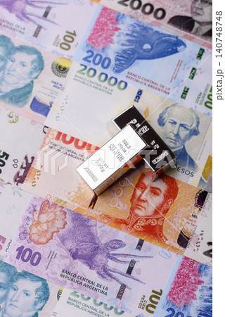 A silver bar, white metal against a backdrop of Argentine money, as a concept for the sales market A silver bar, white metal against a backdrop of Argentine money, as a concept for the sales market 140748748