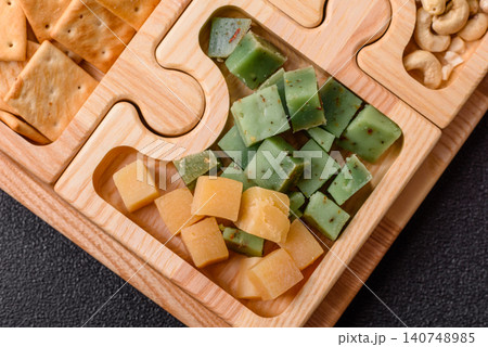 A tray with cubes of mozzarella, and Parmesan cheese, nuts, and crackers. Cheese, crackers, and nuts 140748985