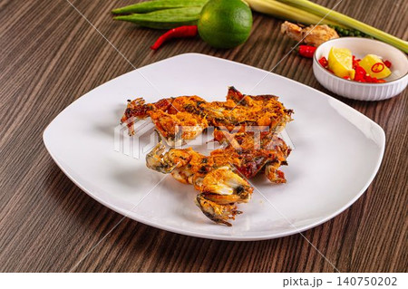 Fried frog legs on white plate with lime chili garnish 140750202