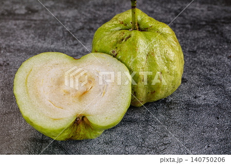 Fresh green guava fruit sliced open on dark textured surface 140750206