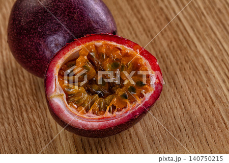 Halved passion fruit with vibrant orange pulp and seeds on wooden surface Halved passion fruit with vibrant orange pulp and seeds on wooden surface 140750215