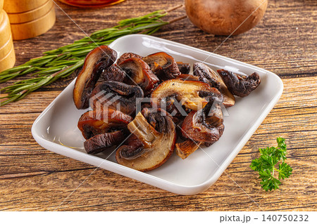 Grilled mushrooms on white plate with rosemary and parsley on rustic wood table Grilled mushrooms on white plate with rosemary and parsley on rustic wood table 140750232