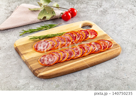 Sliced salami on wooden cutting board with rosemary and cherry tomatoes Sliced salami on wooden cutting board with rosemary and cherry tomatoes 140750235