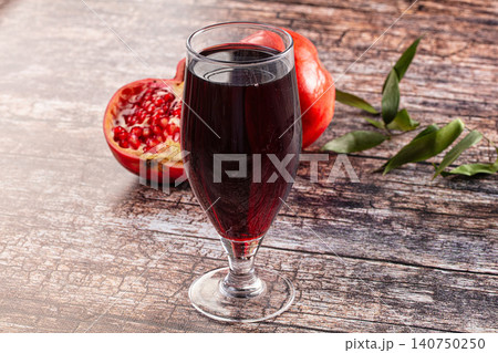 Glass of pomegranate juice with fresh fruit on rustic wooden table Glass of pomegranate juice with fresh fruit on rustic wooden table 140750250
