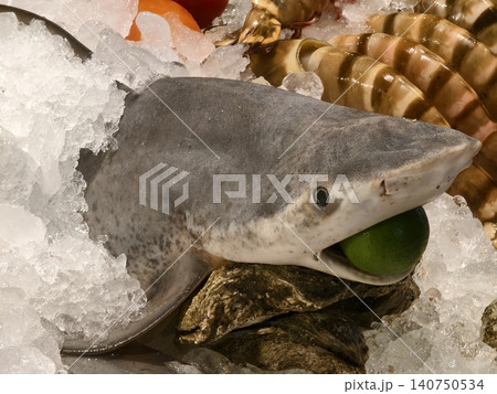 Fresh seafood with fish head. Seafood market scene showcasing shark head on ice with olives Fresh seafood with fish head. Seafood market scene showcasing shark head on ice with olives 140750534