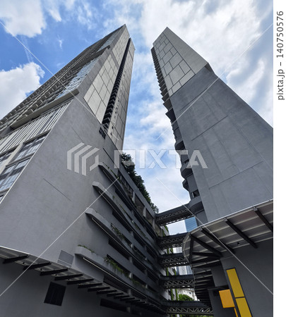 Contemporary concrete highrise structures. Twin concrete towers with sky bridge reaching sky Contemporary concrete highrise structures. Twin concrete towers with sky bridge reaching sky 140750576