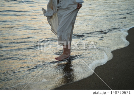 Barefoot in Water by the Shoreline at Sunset 140750671