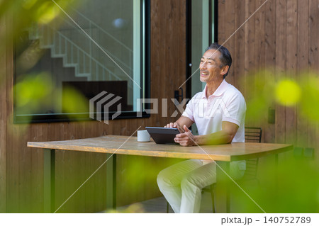 テラスでタブレットを操作しながらコーヒーを飲むシニア男性 テラスでタブレットを操作しながらコーヒーを飲むシニア男性 140752789