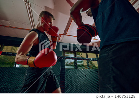 Sweaty boxer preparing defense during intense mitt training in fight gym. Sweaty boxer preparing defense during intense mitt training in fight gym. 140753129