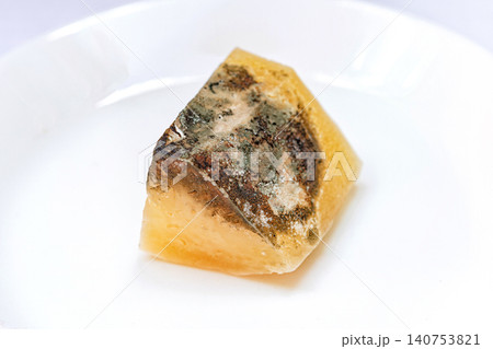 Piece of amber resin with dark inclusions on a white plate in a well lit setting Piece of amber resin with dark inclusions on a white plate in a well lit setting 140753821