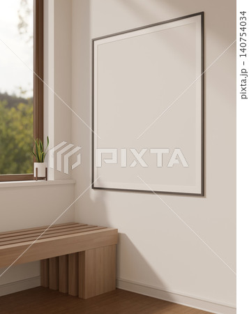Thin black photo poster frame hanging on white wall over wooden bench by window under soft sunlight. 140754034