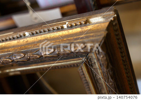 Detailed View of a Vintage Wooden Frame With Intricate Carvings and Gold Accents in an Art Shop Setting 140754076