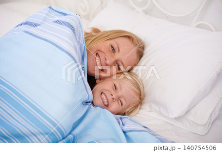 Home, mom and girl with lying in bed together to smile for bonding, relax and chill on break. Parent, kid and happy in bedroom to cuddle with blanket for joy, fun and child development or growth. Home, mom and girl with lying in bed together to smile for bonding, relax and chill on break. Parent, kid and happy in bedroom to cuddle with blanket for joy, fun and child development or growth. 140754506