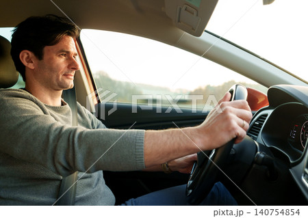 Man driving a car in bright golden sunlight 140754854