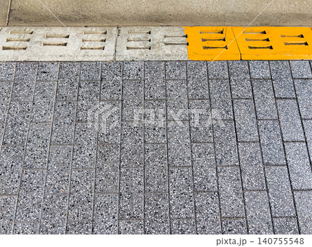 都市の歩道に敷き詰められたインターロッキングブロックと黄色い側溝のテクスチャ 都市の歩道に敷き詰められたインターロッキングブロックと黄色い側溝のテクスチャ 140755548