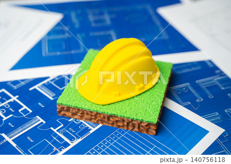 Yellow construction worker's helmet on a plot of land on blueprints drawings. Construction of buildings and infrastructure. Yellow construction worker's helmet on a plot of land on blueprints drawings. Construction of buildings and infrastructure. 140756118