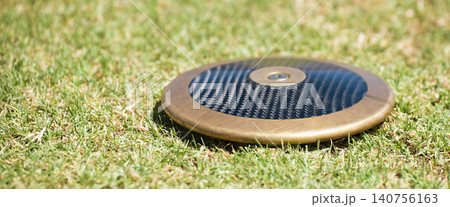 Close up of discuses on grass after impact on grass. Discus throw Close up of discuses on grass after impact on grass. Discus throw 140756163
