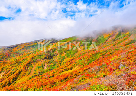 秋の晴れ間 紅葉最盛期の栗駒山・雲間から青空覗く全山紅葉の美しい山肌風景 秋の晴れ間 紅葉最盛期の栗駒山・雲間から青空覗く全山紅葉の美しい山肌風景 140756472