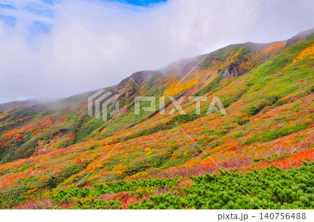 秋の晴れ間 紅葉最盛期の栗駒山・雲間から青空覗く全山紅葉の美しい山肌風景 秋の晴れ間 紅葉最盛期の栗駒山・雲間から青空覗く全山紅葉の美しい山肌風景 140756488
