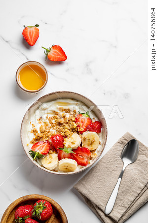 Natural Greek yogurt with granola, banana and strawberries in a bowl on a marble background Natural Greek yogurt with granola, banana and strawberries in a bowl on a marble background 140756864