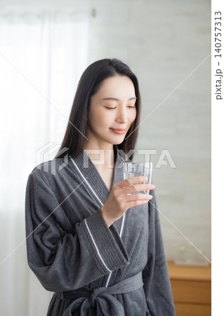 窓辺で水を飲む若い女性 140757313