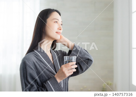 窓辺で水を飲む若い女性 窓辺で水を飲む若い女性 140757316