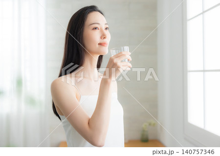 窓辺で水を飲む若い女性　 140757346