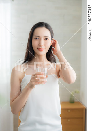 窓辺で水を飲む若い女性 窓辺で水を飲む若い女性 140757348