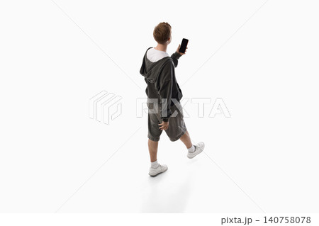 Young man showing smartphone screen while walking isolated on white background. Young man showing smartphone screen while walking isolated on white background. 140758078