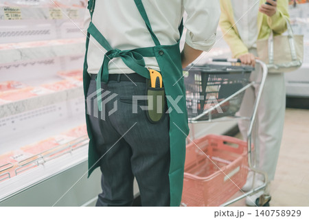 スーパーの精肉売り場でカッターを携帯した店員の後ろ姿と買い物客 スーパーの精肉売り場でカッターを携帯した店員の後ろ姿と買い物客 140758929