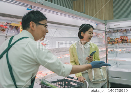 スーパーの精肉売り場で笑顔の女性客に商品を案内する男性店員 スーパーの精肉売り場で笑顔の女性客に商品を案内する男性店員 140758930