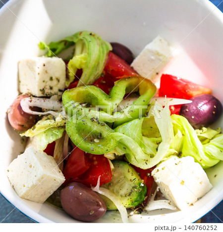 Close-up of fresh Greek salad with tomatoes, cucumbers, olives, feta cheese and olive oil in a white plate Close-up of fresh Greek salad with tomatoes, cucumbers, olives, feta cheese and olive oil in a white plate 140760252
