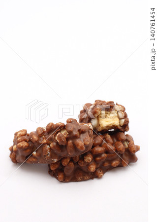 Chocolate-coated cereal clusters, one broken open. Golden center contrasts with dark, textured exterior. Simple white background highlights snack's rich appeal. Perfect for food blogs, recipes Chocolate-coated cereal clusters, one broken open. Golden center contrasts with dark, textured exterior. Simple white background highlights snack's rich appeal. Perfect for food blogs, recipes 140761454