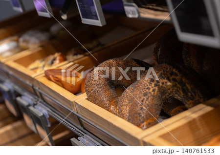Freshly baked bagels displayed in wooden trays at a bakery, with assorted pastries nearby Freshly baked bagels displayed in wooden trays at a bakery, with assorted pastries nearby 140761533