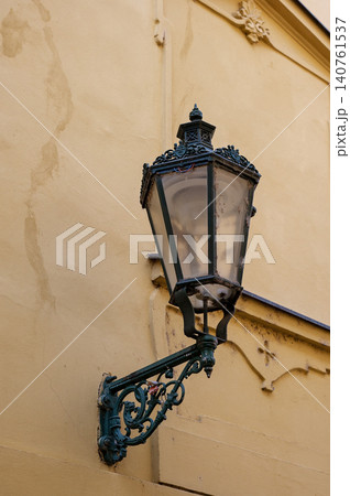 Vintage street lamp mounted on yellow wall with intricate design and glass enclosure Vintage street lamp mounted on yellow wall with intricate design and glass enclosure 140761537
