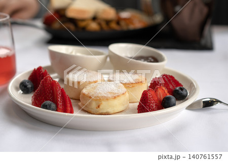 Freshly baked scones with strawberries, blueberries, and sauces served on a white plate at a restaurant 140761557