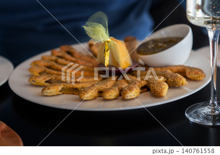 Plate of golden fried fish sticks served with dipping sauce and garnished with decorative ribbon Plate of golden fried fish sticks served with dipping sauce and garnished with decorative ribbon 140761558
