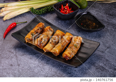 Crispy spring rolls with chili sauce and fresh herbs on dark plate 140761756