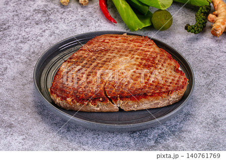 Grilled steak with charred surface on dark plate surrounded by fresh herbs and spices Grilled steak with charred surface on dark plate surrounded by fresh herbs and spices 140761769