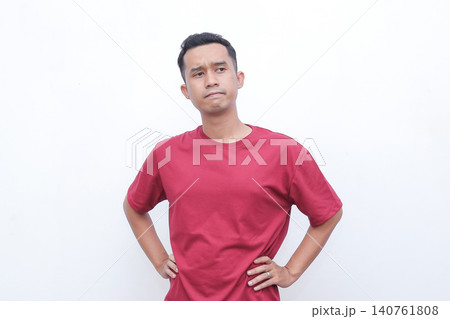 Man shrugs, hands open, showing uncertainty. He wears a simple red tshirt. His expression suggests confusion or indifference. Ideal for situations requiring a gesture of hesitation 140761808
