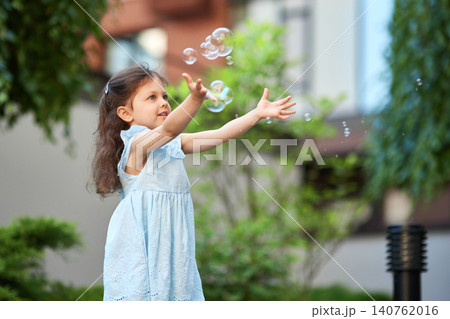Little girl playing with soap bubbles in park, enjoying childhood, summer joy, and discovery. Outdoor recreation Little girl playing with soap bubbles in park, enjoying childhood, summer joy, and discovery. Outdoor recreation 140762016