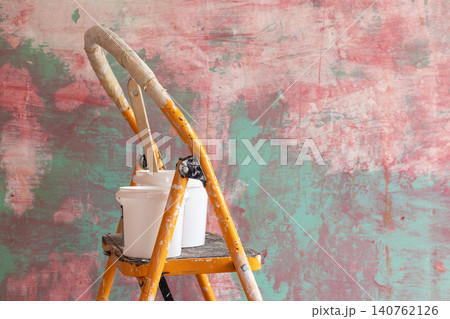 DIY home renovation scene featuring paint-splattered yellow step ladder with paint buckets and wooden mixing stick against colorful textured wall. Interior remodeling, decorating concept copy space DIY home renovation scene featuring paint-splattered yellow step ladder with paint buckets and wooden mixing stick against colorful textured wall. Interior remodeling, decorating concept copy space 140762126