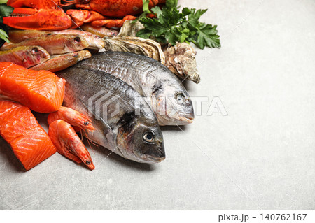 Fresh raw fish and different seafood on light grey table. Space for text Fresh raw fish and different seafood on light grey table. Space for text 140762167
