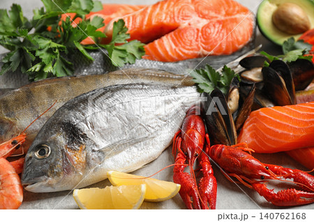 Fresh fish and different seafood on light grey table, closeup Fresh fish and different seafood on light grey table, closeup 140762168