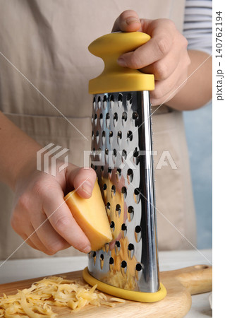 Woman grating fresh cheese at table, closeup Woman grating fresh cheese at table, closeup 140762194