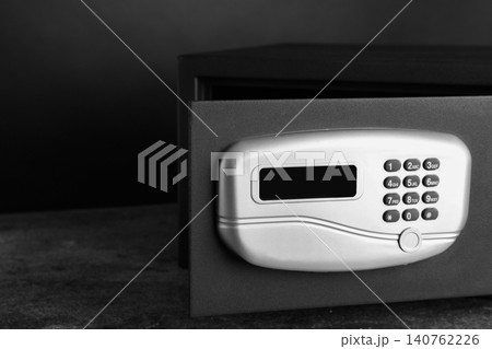 Black steel safe with electronic lock on grey table against dark background, closeup Black steel safe with electronic lock on grey table against dark background, closeup 140762226